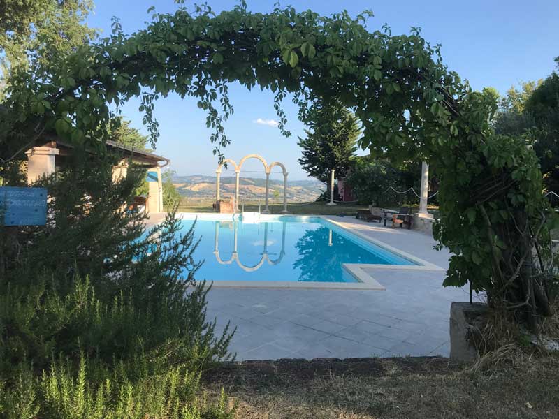 La piscina con il grade spazio attrezzato condivisa tra le case dell' Agriturismo nelle Marche